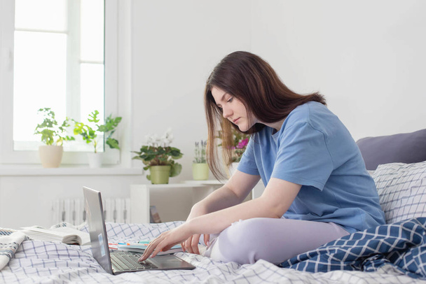 teen girl studying at home on bed with laptop - 写真・画像