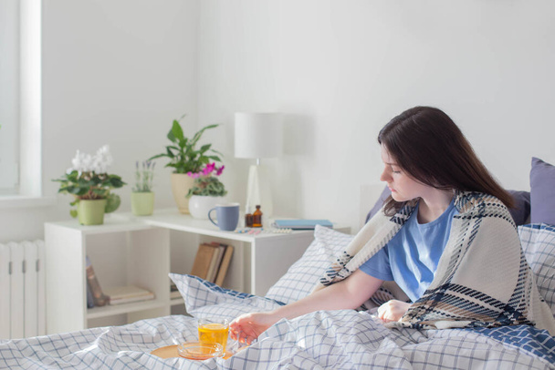 sick teen girl with tea on bed in white room - Foto, Imagen
