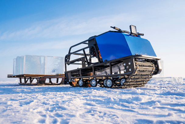 Трактор с прицепом перевозит блоки льда по льду Байкала. Нижний вид. - Фото, изображение