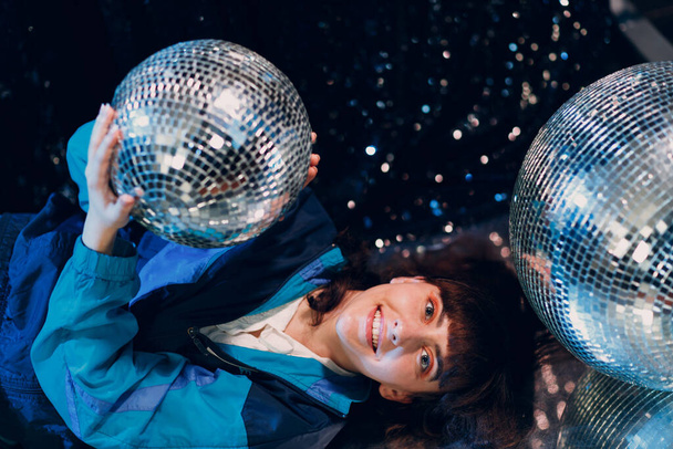 Young sporty woman 80 and 90s style. 90s fashion positive girl at night club disco party with disco ball. - Photo, Image