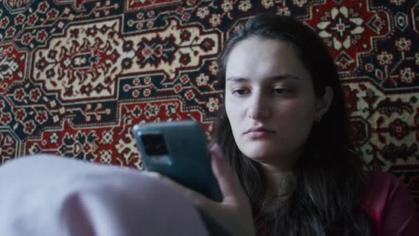 Ein trauriges Mädchen verfolgt die schrecklichen Nachrichten über die russische Offensive auf dem Territorium der Ukraine auf einem Smartphone. Nachrichten über die Spannungen zwischen der Ukraine und Russland. Russische Aggression. Kriegsgefahr - Filmmaterial, Video