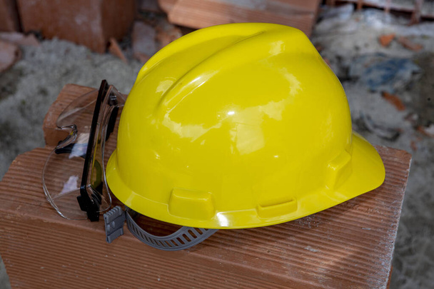Желтый защитный шлем на груде красных кирпичей, на строительной площадке. Сан-Паулу, Бразилия
. - Фото, изображение