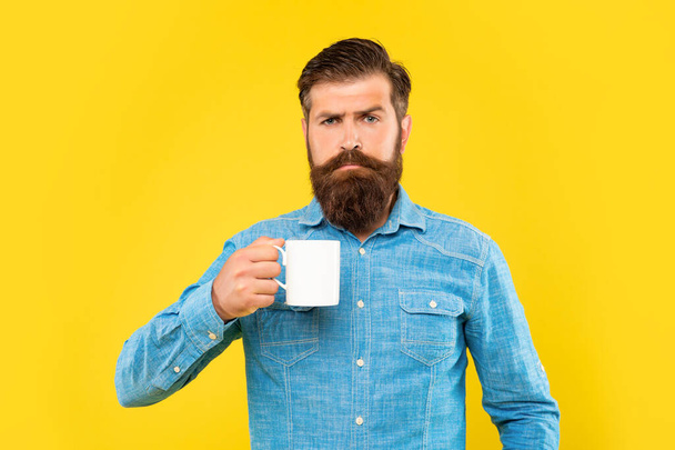 Serious caucasian man holding tea mug yellow background - Фото, зображення