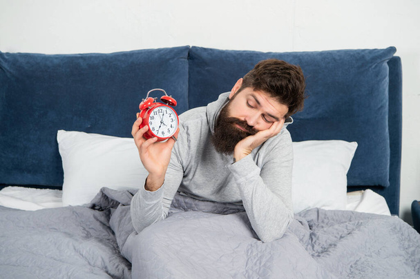 Drowsy man looking at alarm clock being in bed in morning, sleep loss - Φωτογραφία, εικόνα