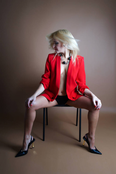 passionate adult woman in a red jacket on brown background.Isolated studio shot - Valokuva, kuva