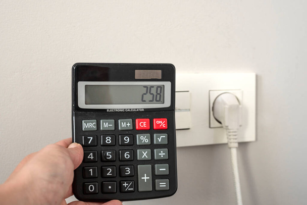 калькулятор рядом с розеткой - концепция повышения цен на электроэнергию - Фото, изображение