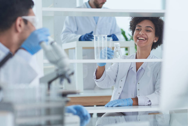 Smiling scientists looking at camera arms crossed in laboratory - Photo, image