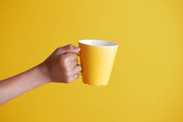 close up of man hand holding mug isolated on yellow  - Fotoğraf, Görsel
