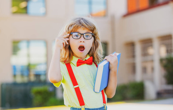 Happy excited kid in glasses is going to school for the first time. Pupil go study. Child boy with bag go to elementary school. Child of primary school. Back to school. - 写真・画像