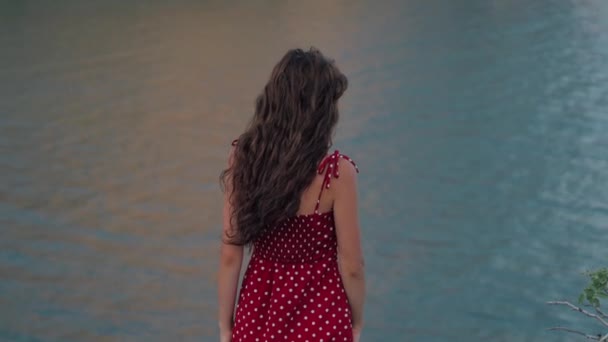 A beautiful girl of Caucasian appearance slowly turns around, smiles and looks at the camera. On the background of the sea. Authentic video. The concept of freedom, joy. Slow motion video - Footage, Video