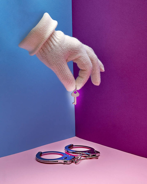 Menottes. Une main dans un gant blanc tient les clés de menottes. geste de la main. - Photo, image