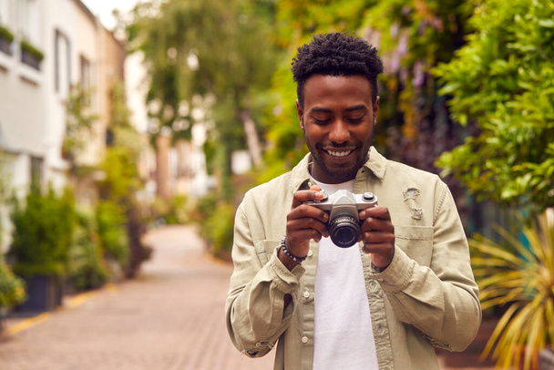 Νεαρός στην πόλη λήψη φωτογραφιών σε ψηφιακή φωτογραφική μηχανή για να δημοσιεύσετε στα μέσα κοινωνικής δικτύωσης - Φωτογραφία, εικόνα