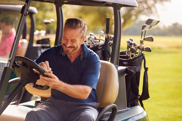 Mature Man Sitting In Buggy Playing Round On Golf And Checking Score Card - Фото, зображення