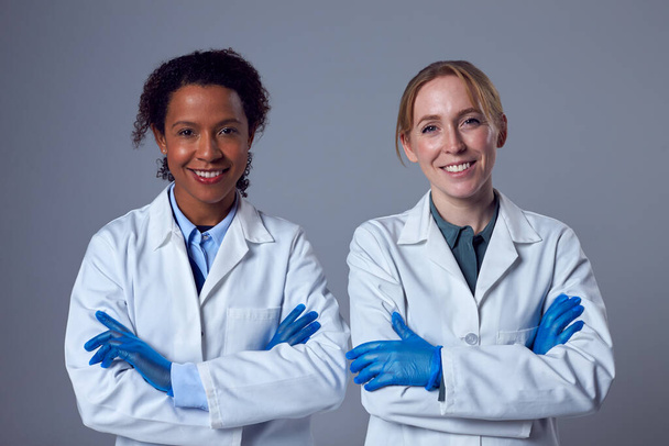 Studio Portrait Of Two Smiling Female Doctors Or Lab Workers In White Coats And Gloves - Zdjęcie, obraz