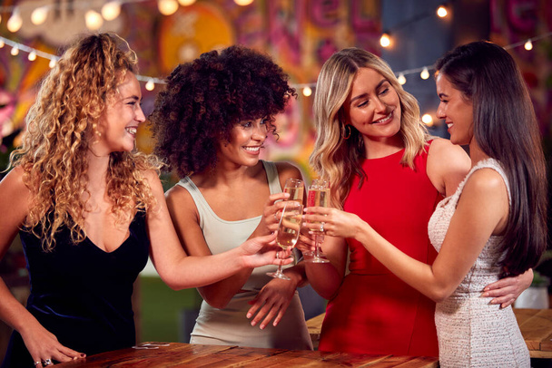 Multi-Cultural Group Of Female Friends Enjoying Night Out Drinking In Bar Together Making A Toast - Foto, Imagem