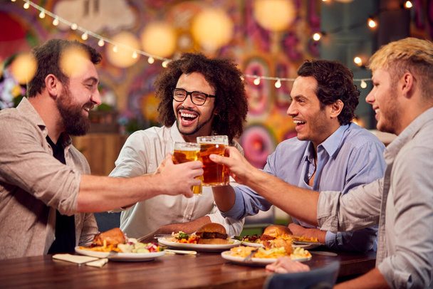Multi-Cultural Group Of Male Friends Enjoying Night Out Eating Meal And Drinking In Restaurant - Fotoğraf, Görsel