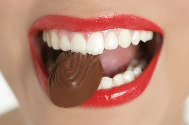 Chocolate sweet in beautiful woman mouth - 写真・画像