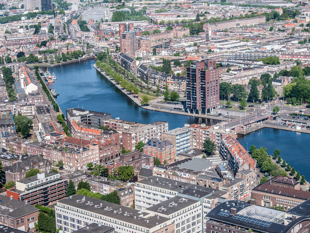 Paesaggio urbano aereo di edifici, canali, ponti e piccole aree verdi nella città di Rotterdam, giornata di sole con un cielo grigiastro con lo skyline sullo sfondo nell'Olanda meridionale, Paesi Bassi - Foto, immagini