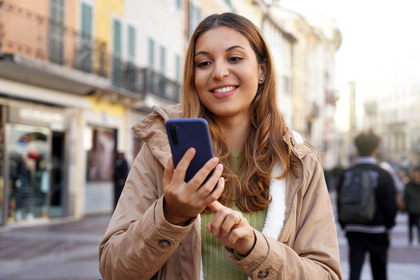 Schülerin benutzt Smartphone in Fußgängerzone der Altstadt in Europa - Foto, Bild