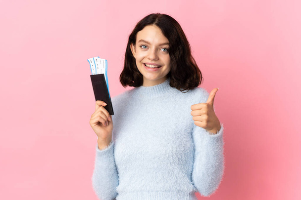 Teenager Ukrainian girl isolated on pink background in vacation holding a passport and plane with thumb up - Foto, Imagen