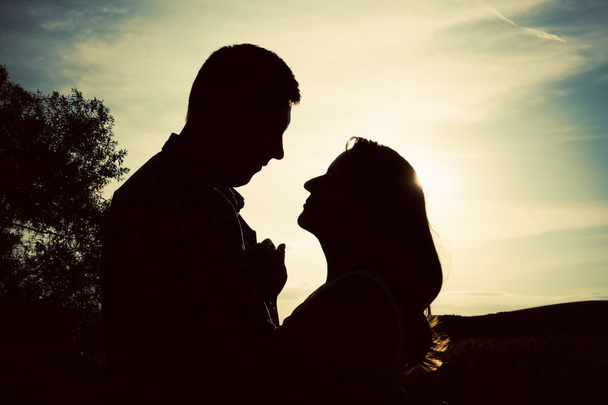 Silhouette of loving couple holding hands in heart shape over or - Photo, Image