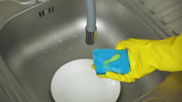 Χέρια σε κίτρινα προστατευτικά γάντια απλώστε απορρυπαντικό και πλύνετε την πλάκα - Πλάνα, βίντεο