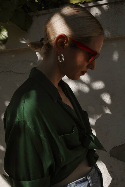 Profile portrait of young blonde woman posing outdoor, dark exposure. - Фото, изображение