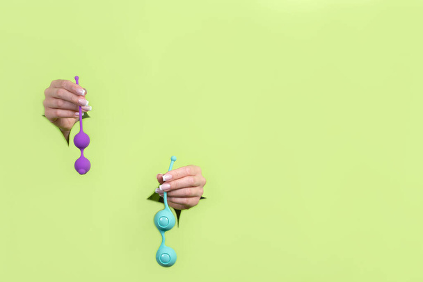 Sex toys on a green background. Vaginal Kegel balls. Copy space. Leisure and recreation for adults. - 写真・画像