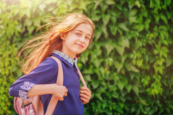 Школярка в блакитній сукні з білим коміром і рюкзаком в сонячний день. Назад до школи
. - Фото, зображення