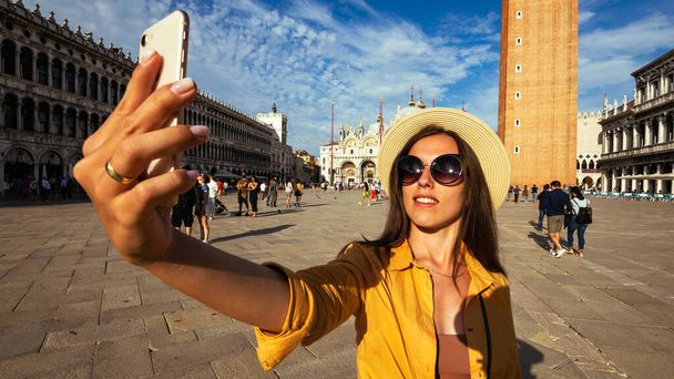 Travel influencers Βενετία νησί. Βαφή κτίριο σπίτι στην Ευρώπη Venezia πόλη. Φωτογράφος blogger κορίτσι με smartphone στην πλατεία Σαν Μάρκο της Βενετίας. Ταξιδεύοντας και ελεύθερος επαγγελματίας, σύγχρονος τρόπος ζωής - Φωτογραφία, εικόνα