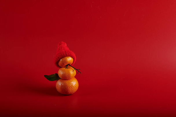 Mandarine Schneemann mit Weihnachtsmütze auf rotem Hintergrund - Foto, Bild