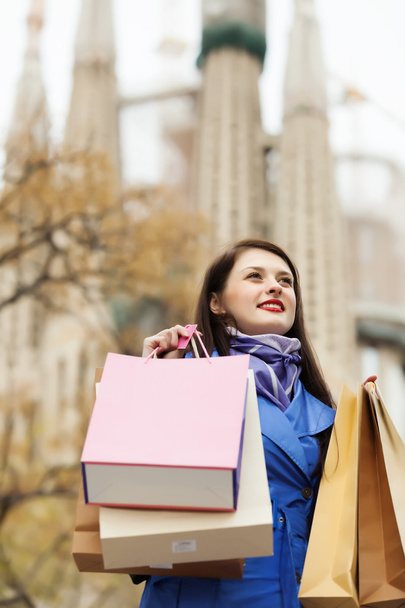 Mujer con bolsas de compras contra Sagrada familia
 - Foto, Imagen