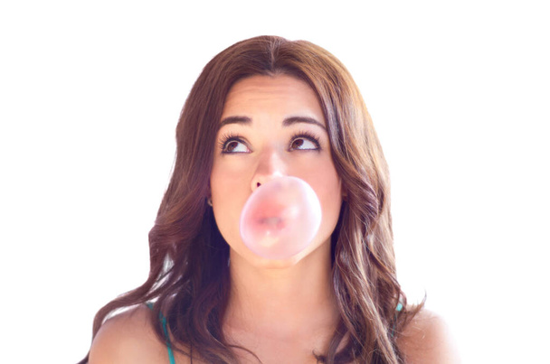 Blowing bubbles. An attractive young woman blow bubbles with gum. - Foto, Bild