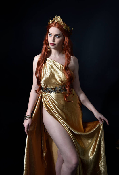  Portret pięknej modelki ubranej w grecką boginię toga, pozującej eleganckimi ruchami gestu na tle studia. - Zdjęcie, obraz