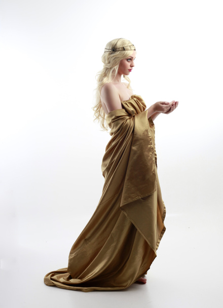  Portret pięknej modelki ubranej w grecką boginię toga, pozującej eleganckimi ruchami gestu na tle studia. - Zdjęcie, obraz