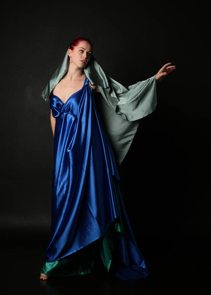  Retrato de comprimento total de modelo muito feminino vestindo vestido de toga deusa grega, posando com movimentos gestuais elegantes em um fundo de estúdio. - Foto, Imagem