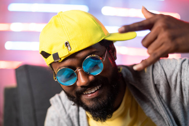 Nahaufnahme des singenden Hip-Hop-Rappers mit Blick in die Kamera auf Neonhintergrund - Konzert von Hip-Hop-Musik, professioneller Sängerin und Unterhaltung - Foto, Bild