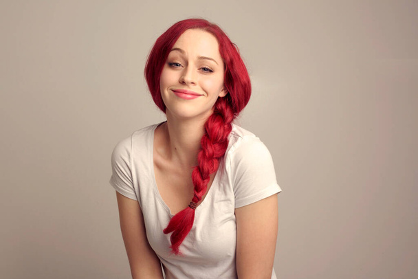 κοντινό πορτραίτο όμορφου γυναικείου μοντέλου με κόκκινα μαλλιά σε πλεξούδα, που εκφράζει συναίσθημα πάνω από την κορυφαία έκφραση προσώπου σε φόντο στούντιο. - Φωτογραφία, εικόνα