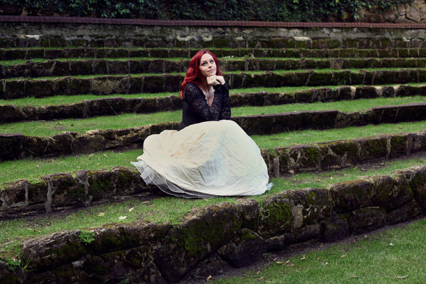 Pełna długość portret rudowłosej kobiety w pięknym gotyckim stroju sukni, spacery po okolicy z romantycznym tle architektury kamienia zamku. - Zdjęcie, obraz