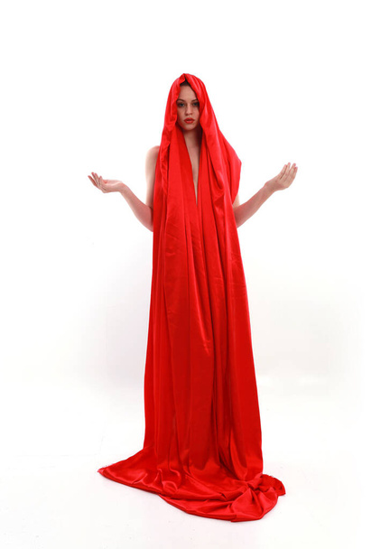 Full length portrait of red haired woman wearing a  beautiful sexy silk gown costume, standing pose with creative arm gestures, isolated on white studio background. - 写真・画像