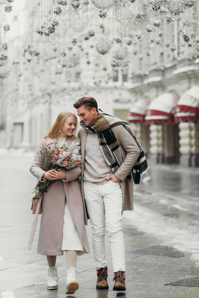 miłość para miłość płaszcz beżowy szary biały bukiet kwiaty czułość uczucia spacer uścisk data - Zdjęcie, obraz