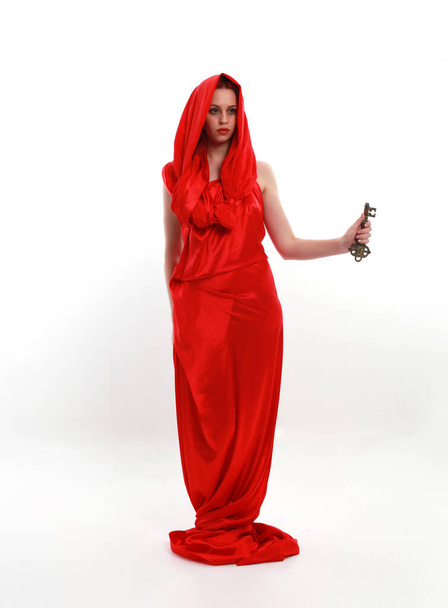 Full length portrait of red haired woman wearing a  beautiful sexy silk gown costume, standing pose with creative arm gestures, isolated on white studio background. - Photo, Image
