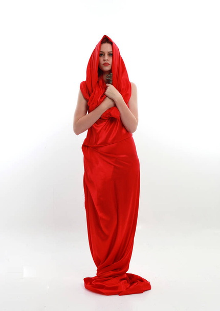 Полноразмерный портрет рыжеволосой женщины в красивом сексуальном шелковом платье, стоящей позы с творческими жестами руки, изолированные на белом фоне студии. - Фото, изображение