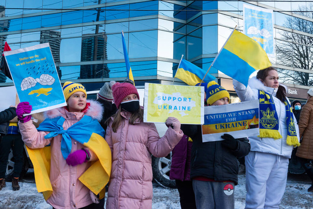 Toronto, ON, Kanada 25 Şubat 2022: Ukrayna yakınlarındaki Rus saldırganların Ukrayna 'daki savaşına karşı düzenlenen gösteri sırasında Ukrayna konsolosluğu yakınlarında bayraklı protestocular. - Fotoğraf, Görsel