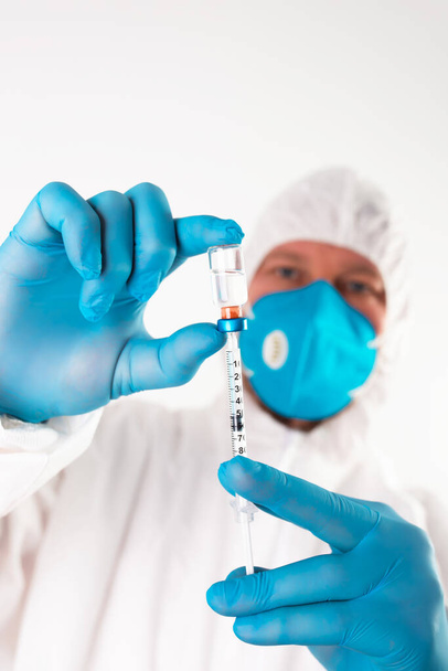 COVID-19 coronavirus vaccine. Vaccination concept. Doctor's hand in blue gloves hold medicine vaccine vial bottle and syringe.  - Zdjęcie, obraz