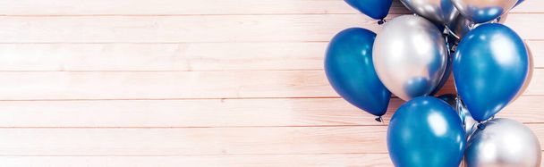 zilveren en blauwe ballonnen op houten ondergrond. Concept van geluk, vreugde, verjaardag. Begrepen Ruimte. spandoek - Foto, afbeelding