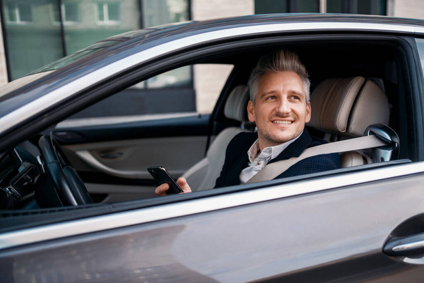The entrepreneur is in the car. The manager is a professional in a business suit. The lawyer smiles and looks towards the gray hair. - Фото, изображение