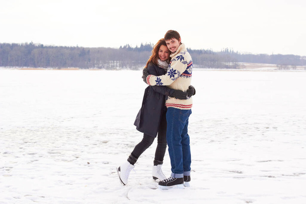 Winter romance. A young couple on an ice skating date at a frozen natural lake. - Фото, зображення