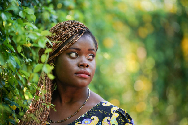 Joven atractiva mujer de piel negra, peinado afro, en el fondo de la naturaleza - Foto, Imagen