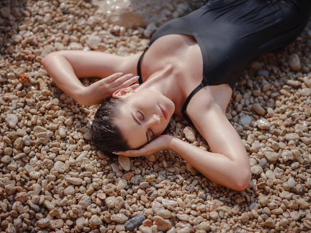岩の多いビーチで美しい女性のライフスタイル水着写真撮影。健康的なライフスタイルの屋外です。人が幸福と自由を感じるとき、静かでさまよう欲望の概念の瞬間. - 写真・画像